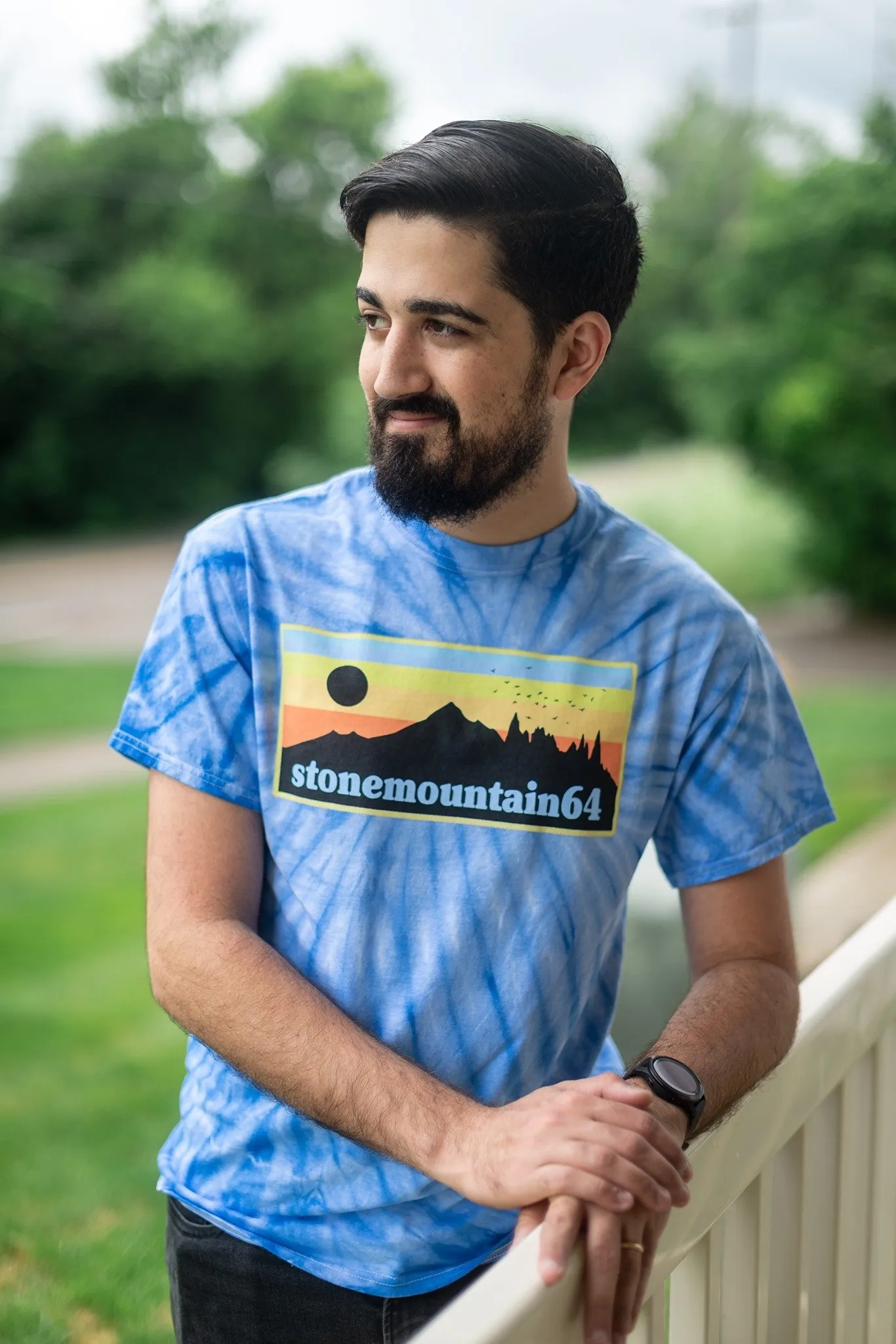 Alex Kumar leaning on a railing outdoors, wearing a StoneMountain64 t-shirt